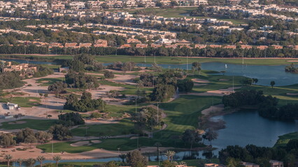 Aerial view to Golf course with green lawn and lakes, villa houses behind it timelapse.