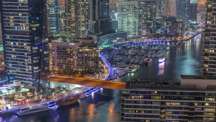 Aerial view to Dubai marina skyscrapers around canal with floating boats night timelapse