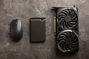 External HDD, graphics card and computer mouse on a black cement background. Computer components. Place to copy.