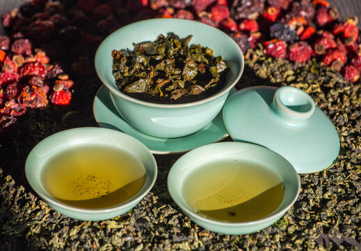 Gaivan and bowls with green tea and tea leaves on a brown background close-up,selective focus. Tea ceremony. Traditional Chinese tea ware.Gaiwan cup.Zhu yao ceramic.Chinese ceramics.Blurred defocused.