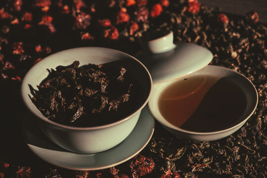 Gaivan and bowls with green tea and tea leaves on a brown background close-up, selective focus. Tea ceremony. Traditional Chinese tea ware. Gaiwan cup. Zhu yao ceramic. Chinese ceramics. Relax. 