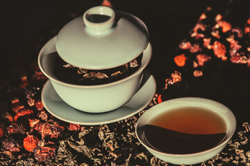 Gaivan and bowls with green tea and tea leaves on a brown background close-up,selective focus. Tea ceremony. Traditional Chinese tea ware.Gaiwan cup.Zhu yao ceramic.Chinese ceramics.Blurred defocused.