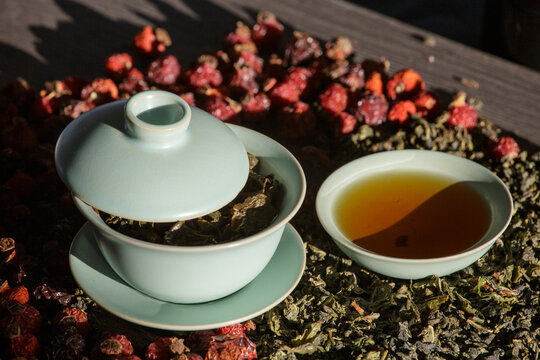 Gaivan and bowls with green tea and tea leaves on a brown background close-up,selective focus. Tea ceremony. Traditional Chinese tea ware.Gaiwan cup.Zhu yao ceramic.Chinese ceramics.Blurred defocused.