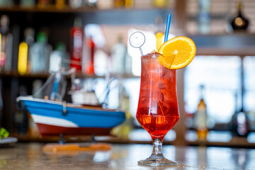 fresh red cocktail with orange on the bar counter. Against the background of a wooden boat