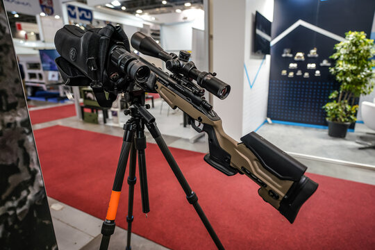 Brno, Czechia - October 08, 2021: Modern rifle mounted on large tripod with sniper scope optics manufactured by Sightmark at top displayed at weapons and defence fair
