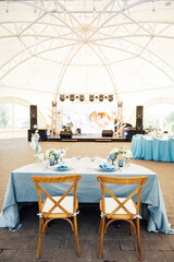 Wedding tables for guests with a blue tablecloth. Decorated with premium glasses and flowers