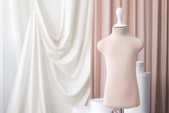 Baby mannequin in pink pastel color in the atelier studio on the background of fabrics.