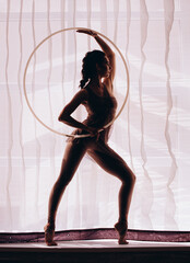 Silhouette of gymnast woman dancing with hula hoop