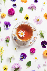 Herbal tea in a vintage porcelain mug with spring and summer flowers on white background. Flat lay, bright colorful pattern, top view. Summer country creative concept.