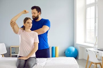 Physiotherapy specialist working with female patient. Male doctor, chiropractor, physiotherapist or...