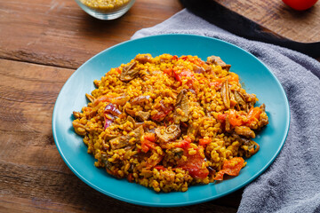 A large dish of bulgur with vegetables and mushrooms on a table on a napkin.