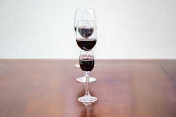 Three red wine glasses of different sizes aligned in selective focus with depth of field blur 
