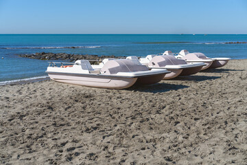 White catamarans are parked on a sandy beach against the backdrop of a blue sea and a cloudless sky