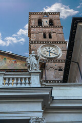 a fragment of the facade of a Roman cathedral with a beautiful tower clock and a statue of a saint...