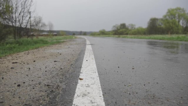 An empty wet road after the rain. The car drives along a slippery dangerous path without oncoming traffic. Asphalt and road markings without people.