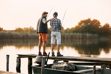 Back view of happy man and his senior father enjoy in freshwater fishing.
