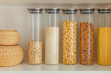 Organization of storage in the kitchen. Pasta, rice and cereal in glass containers on a kitchen shelf. Zero waste storage