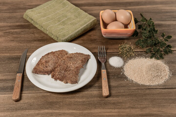 Veal milanese presented on the table with ingredients