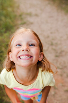 Child funny face. Kid teasing. Girl laughing in sunny summer day