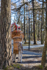 An Indian Native American in a national costume stands in the park among the trees in Svetlogorsk Raushen, Kalinigrad region, Russia, near the Baltic sea. 