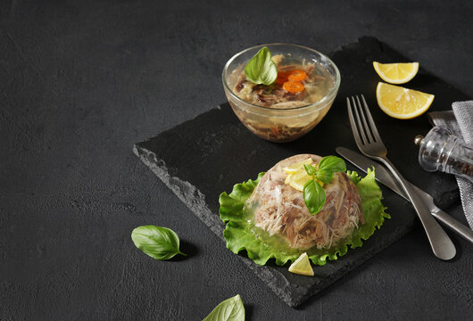 meat aspic, jellied slow cooked meat on a leaf of salad on a dark background, selective focus. copy space