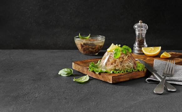 meat aspic, jellied slow cooked meat on a leaf of salad on a dark background . copy space