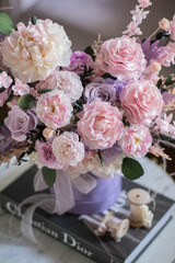 Beautiful composition with peonies and roses in a purpl box on pink chair. Bouquet of tenders peonies a girl for mother's day, valentine's day, Woman's day 8 march.