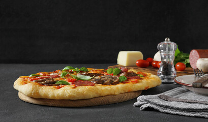 Pizza with mushrooms Served On dark Table, ingredients in the back. copy space