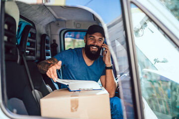 A young bearded delivery man talking with customer and carrying a package to a customer's home...