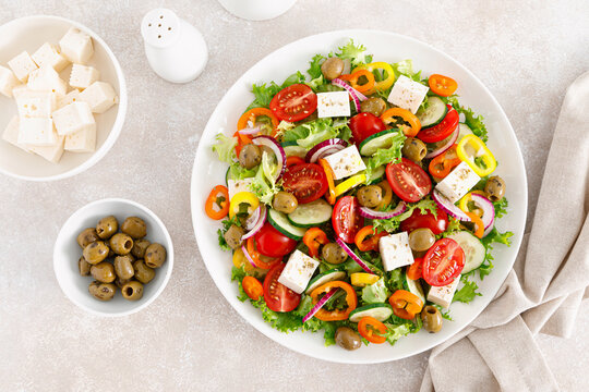 Greek salad with feta cheese, tomatoes, cucumbers, pepper, red onion and green olives. Top view