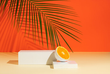 Cut in half orange fruit and tropical palm leaf on product podium. Summer food minimal concept. Suitable for Product Display and Business Concept.