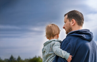 Fatherhood and single father concept. Father holding his child looking at the beautiful dark sky