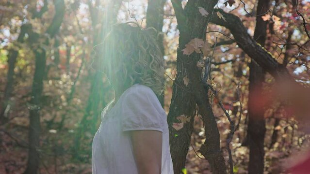 Beautiful woman in forest slowly turns towards camera while taking in nature