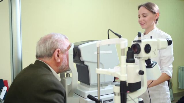 doctor examines elderly man's eye on screen of autorefractometer. 