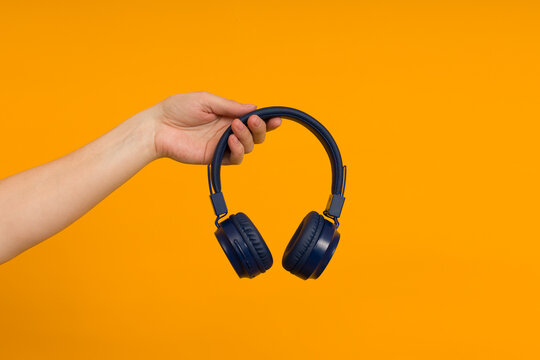 female hand holds modern headphones on a colored background