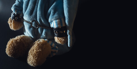 Toy bear is kneeling, facing the wall, hands behind his back in handcuffs. Child abuse. Abduction...