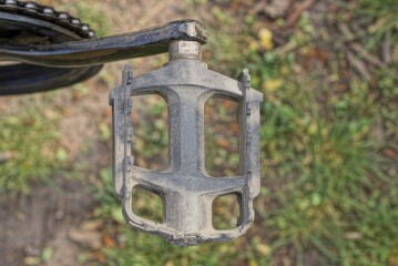 Fototapeta premium one gray metal pedal on a bicycle on the background of green grass on the street
