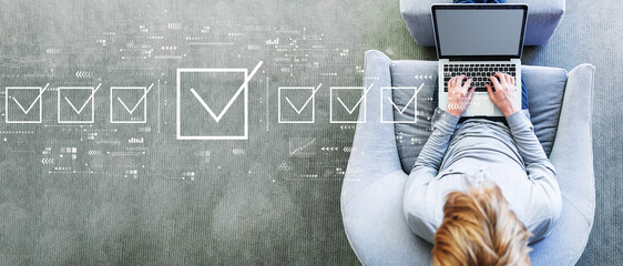 Checklist concept with man using a laptop in a modern gray chair