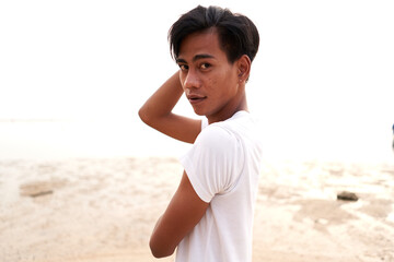 Fototapeta premium Sensual asian man looking to the camera in front of the sea