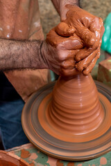 Craft hands making a clay pot. Men's hands. Potter at work. 
Creating pottery vase from fresh wet clay on pottery wheel. Creation. Working potter.