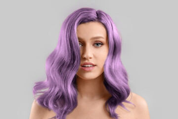 Beautiful young woman with purple hair on grey background - obrazy, fototapety, plakaty