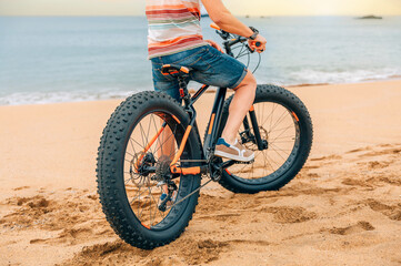 Fat bike on the beach with unrecognizable guy riding on it