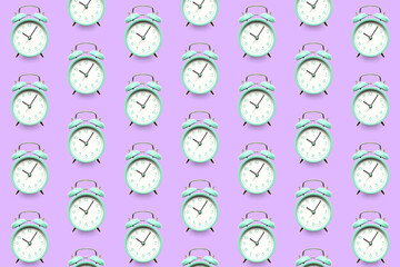 Many alarm clocks on lilac background. Pattern for design