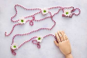 Wooden hand with pink beads and chrysanthemum flowers on white background