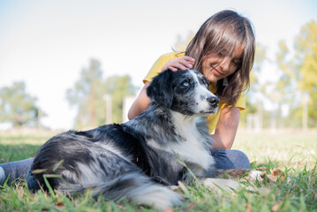 girl with border collie dog cuddling in park in the afternoon
