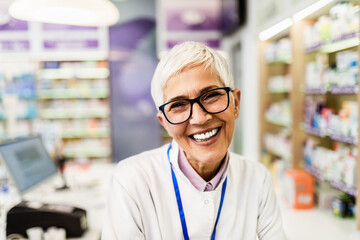 Fototapeta na wymiar Portrait of a smiling mature healthcare worker in modern pharmacy.
