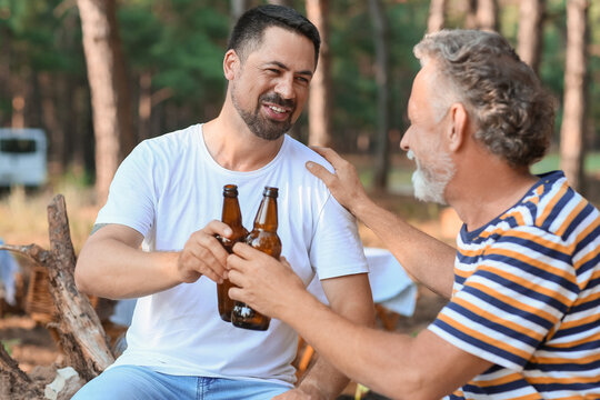 Handsome man with his father drinking beer in forest