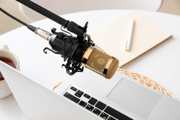 Stand with professional microphone and laptop on light table in room