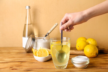 Woman mixing water with baking soda on wooden table