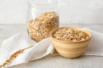 Bowl and jar of raw oatmeal on table